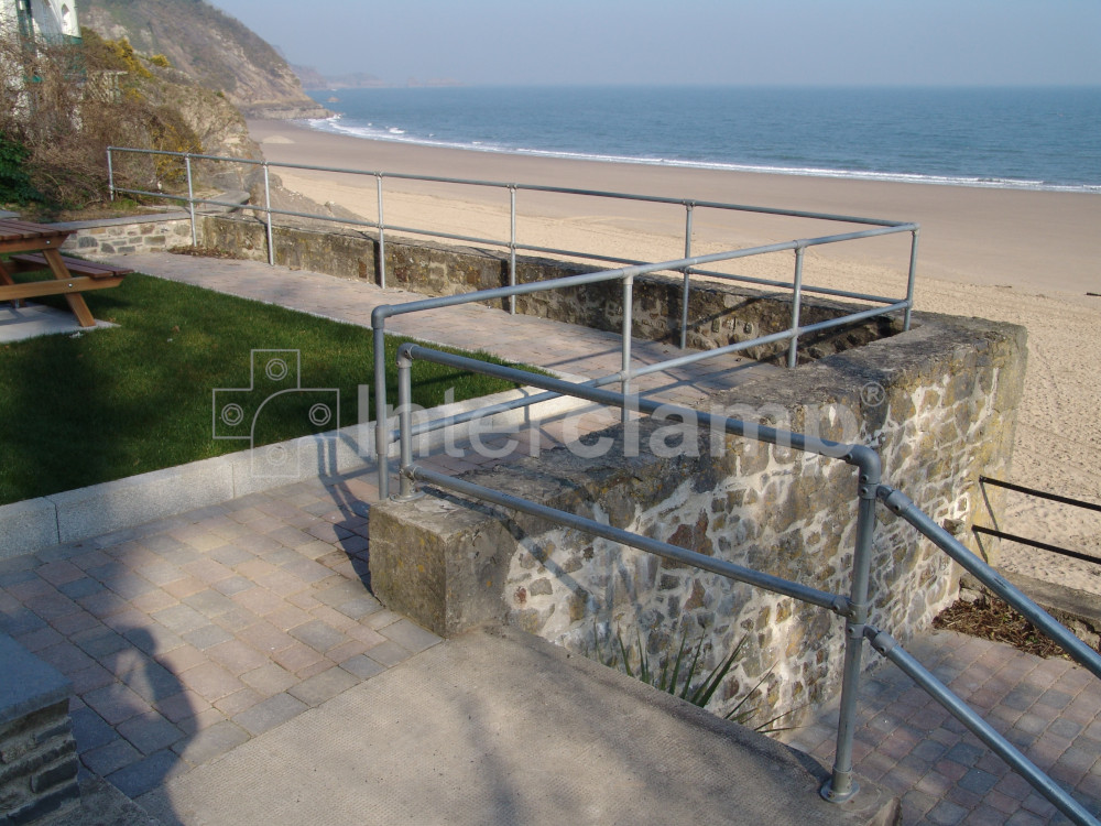 Seaside town harbour viewing area with an Interclamp tube clamp handrail installed along the edge, providing safety for visitors admiring the boats and water.